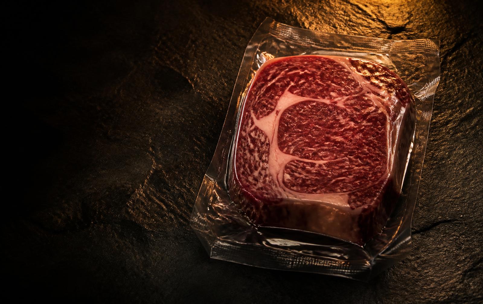 Premium vacuum-packed beef on dark stone with warm bronze lighting